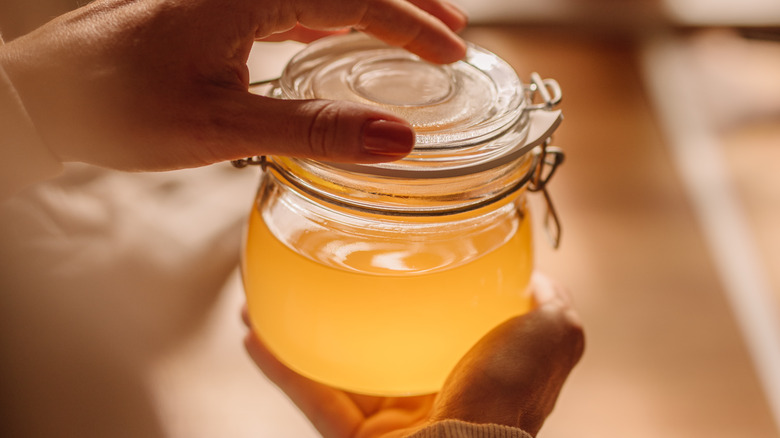 hands holding sealed jar of clarified butter