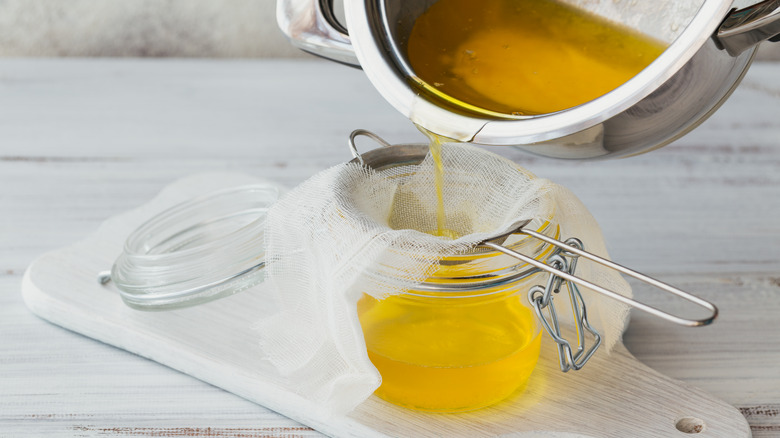 pan with melted butter being strained into jar