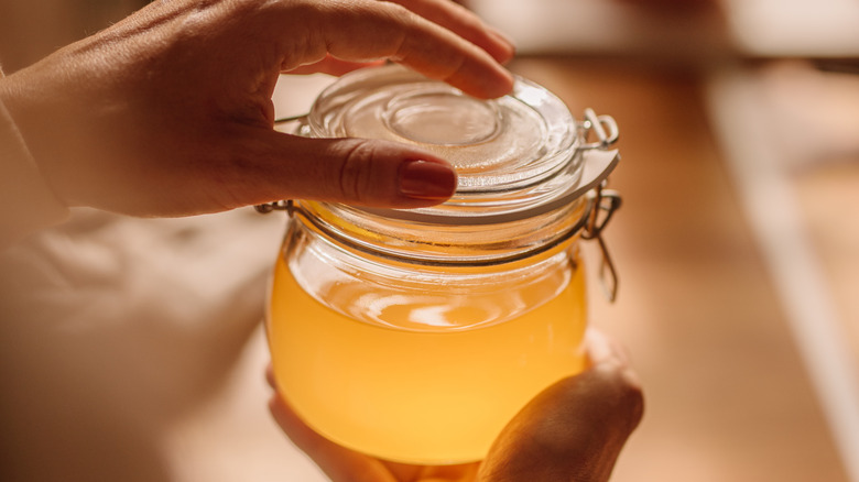 hands holding sealed jar of clarified butter