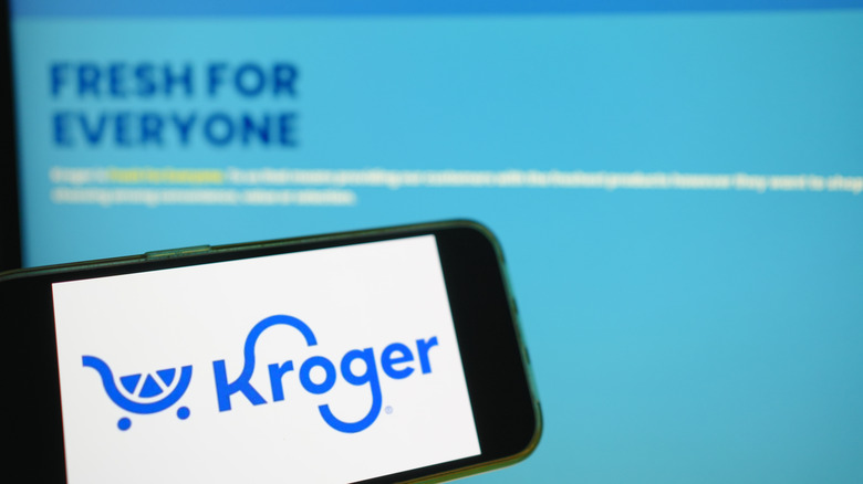A phone with the Kroger app open in front of a computer on the Kroger website.