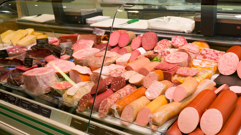 Deli counter display with various cold cuts including bologna, salami, and other meats