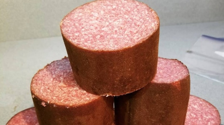 Thick cuts of a Lebanon bologna chub stacked on a countertop