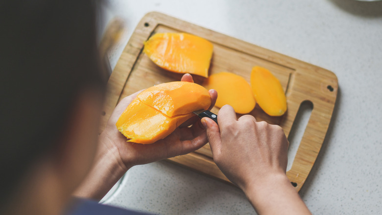 Someone slicing mango
