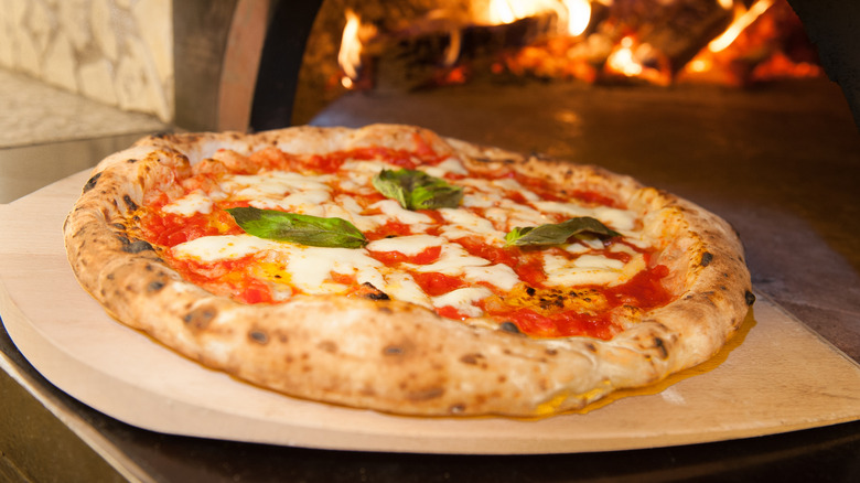 pulling margherita pizza from the oven