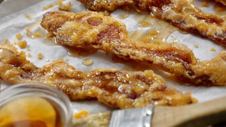 Candied bacon on parchment paper on pan.