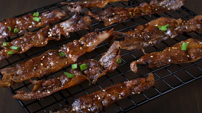 Candied bacon with green onions on cooling rack.