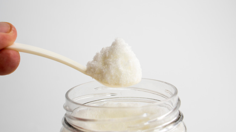 Hand scooping out a teaspoon of MSG