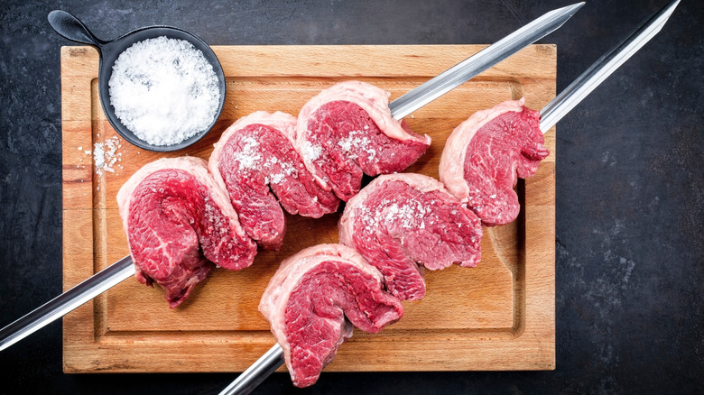Raw picanha steaks seasoned with salt on a skewer