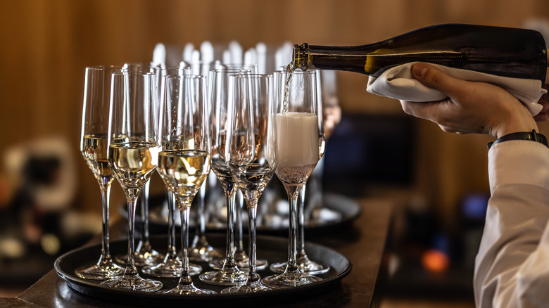 A bartender pouring champagne into glasses.