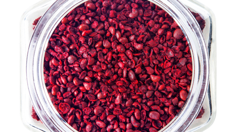 Bird's eye view of open glass bottle of sumac berries