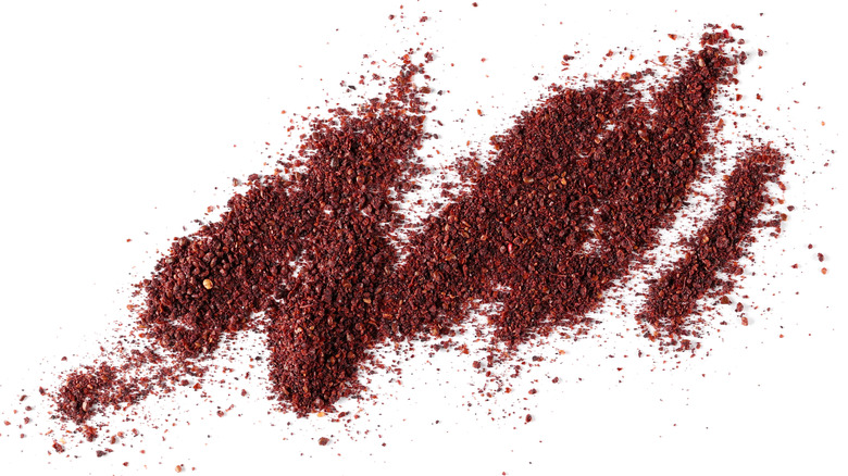 Piles of dried ground sumac on white background