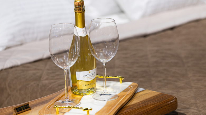 bottle of Prosecco on a wooden tray with two wine glasses