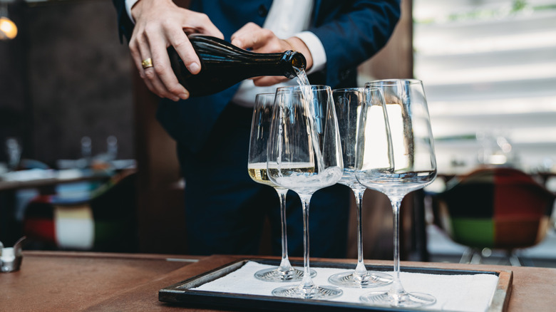 A waiter pouring Prosecco into glasses at a nice establishment