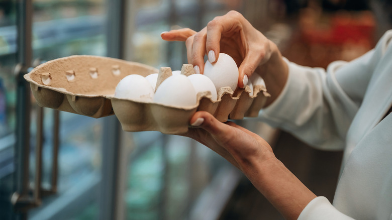 A person checking under the lid of their store-bought eggs