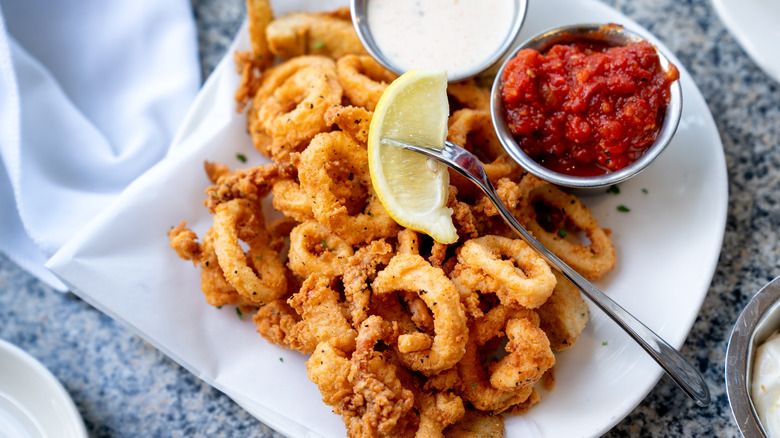 Plate of fried calamari with fresh lemon wedges 