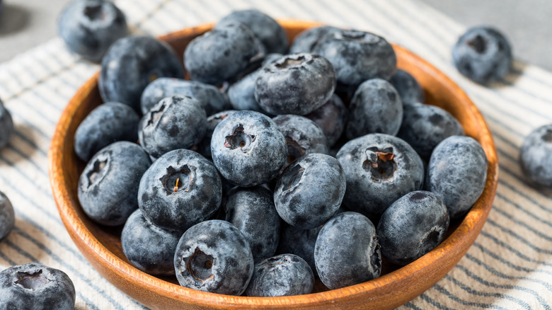 A bowl of fresh blueberries on a striped towel