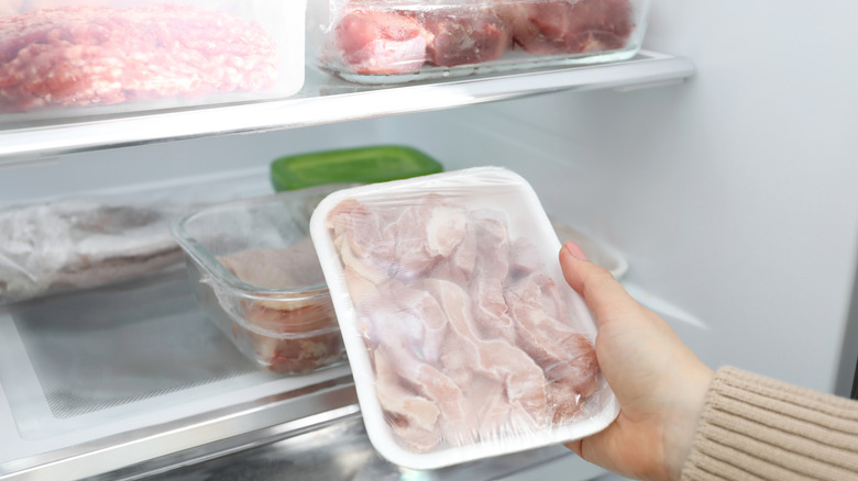 person placing a package of meat into the fridge