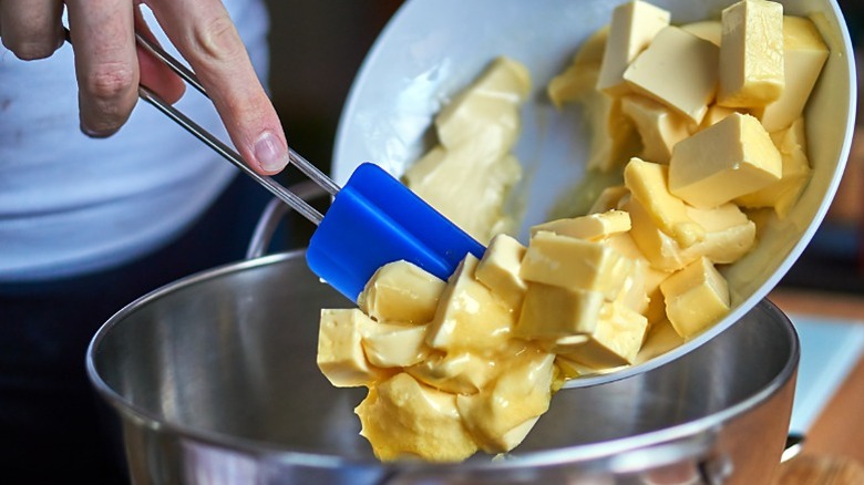 Scooping cubes of butter into mixing bowl