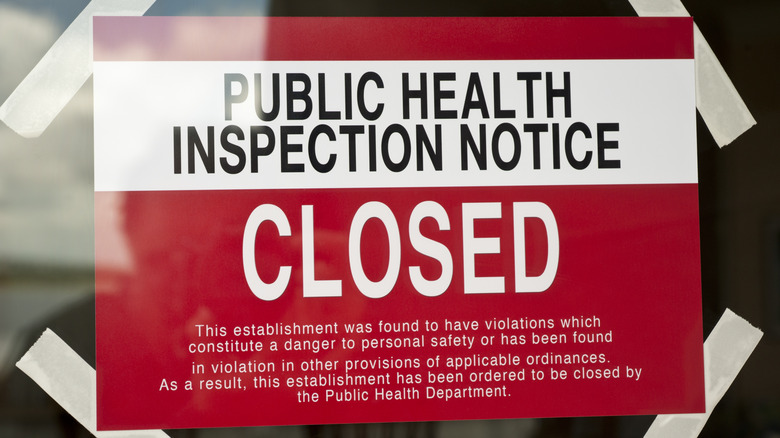 A sign announcing a restaurant's closure due to health code violations.