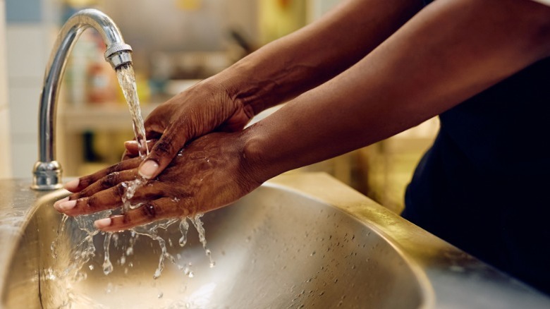 A pair of hands being washed in a sink.