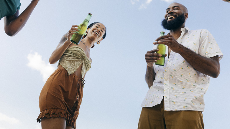 Two people hold beers outside