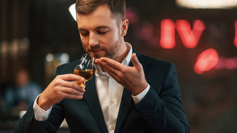 Person smelling bourbon in glass