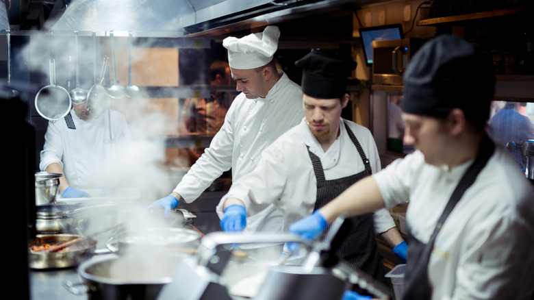 A team of chefs prepare meals in a busy restaurant kitchen.