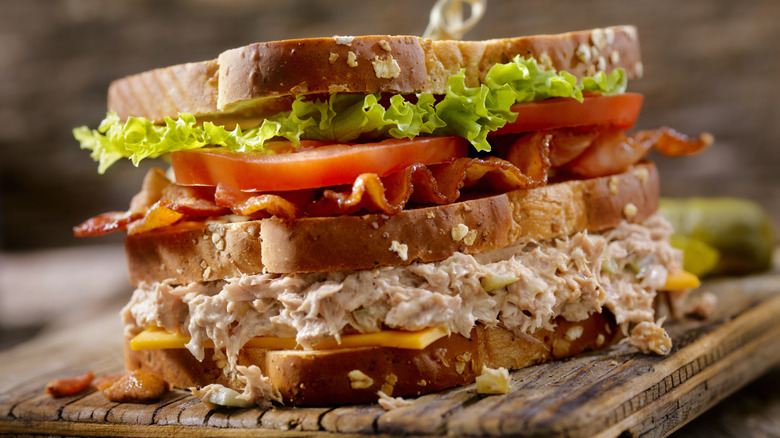 Tuna salad club sandwich on toast, placed on top of a cutting board