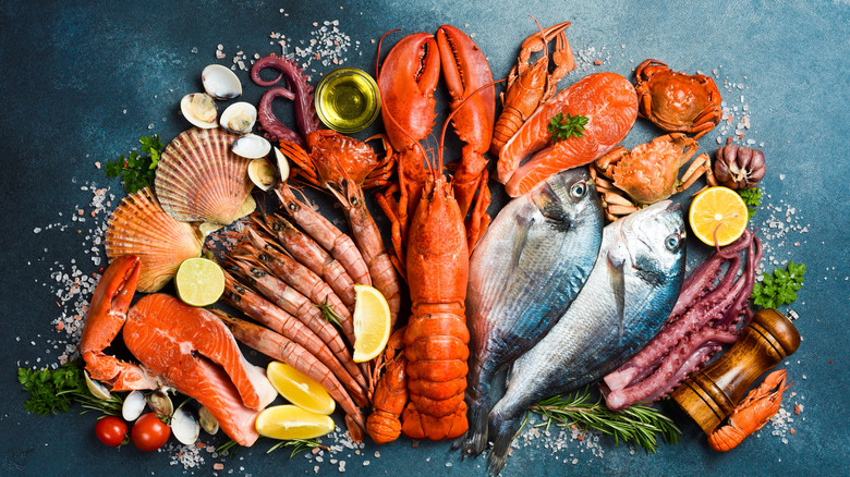 An array of fresh seafood with seasoning and fresh garnish, set against a dark, textured background.