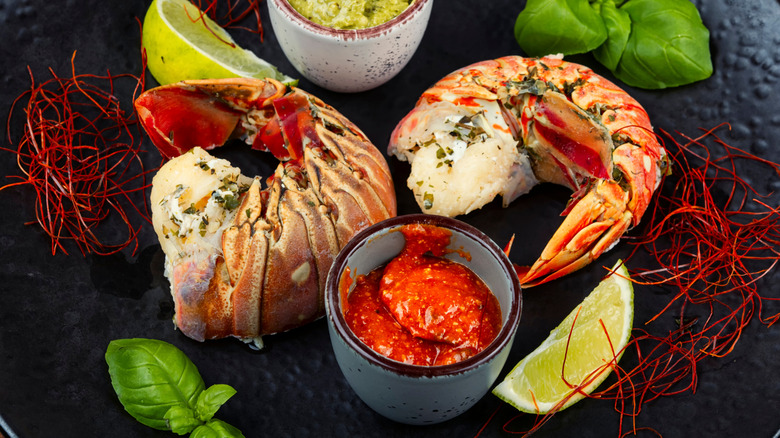Cooked spiny lobster tail surrounded by a variety of sauces