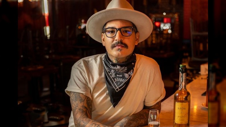 Gilbert Marquez at a bar with a bottle of Ilegal Mezcal