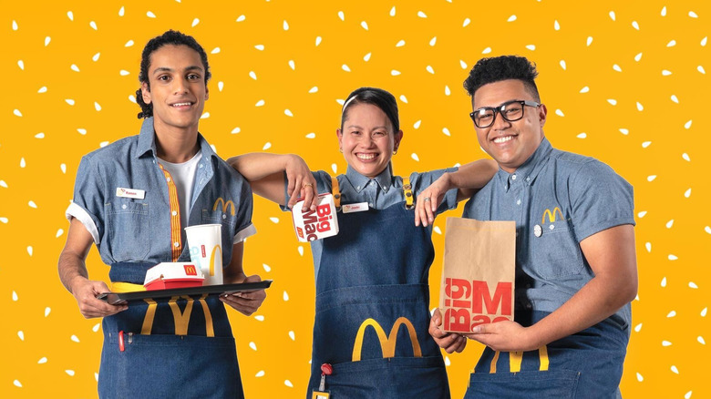 three mcdonald's employees holding food