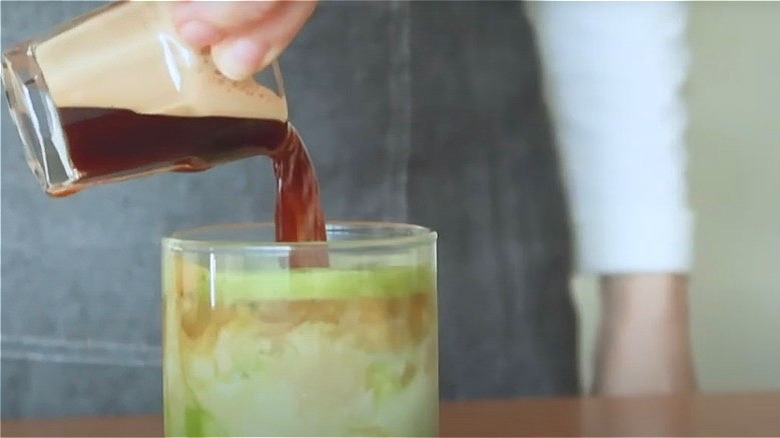 barista pouring shot of espresso into matcha drink