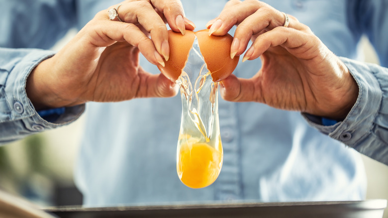 An individual cracking an egg into a pan