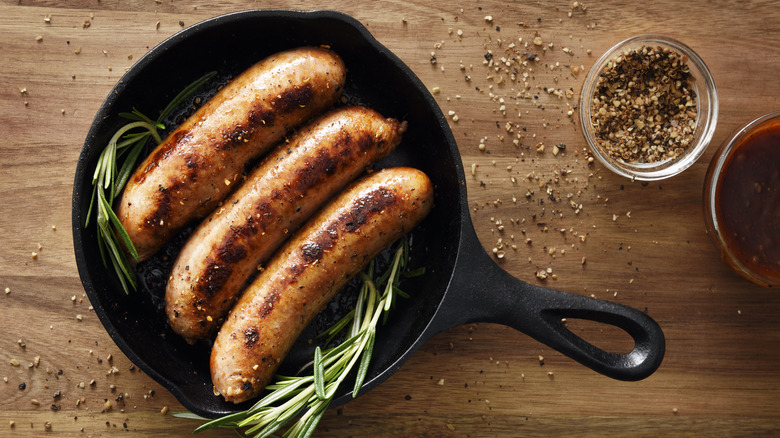 Sausages cooking in a cast iron skillet.
