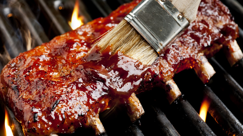 A close-up of sauce being brushed on Chicago-style baby back ribs