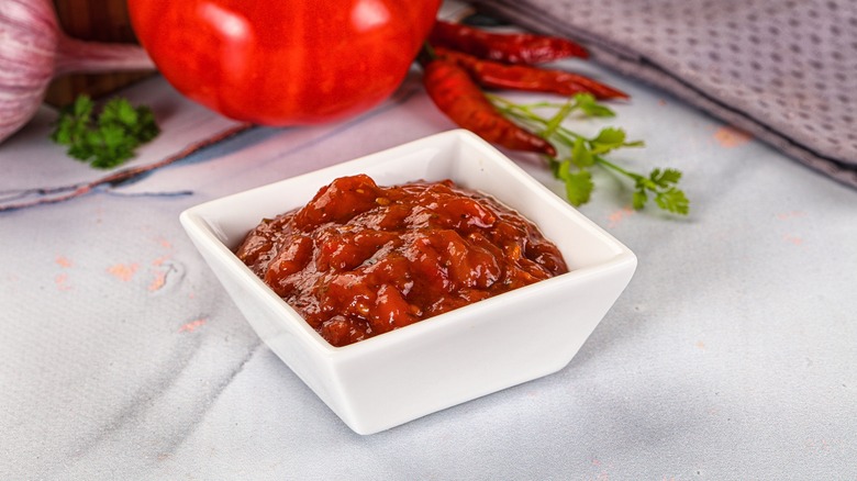 salsa in a white bowl with some ingredients in background