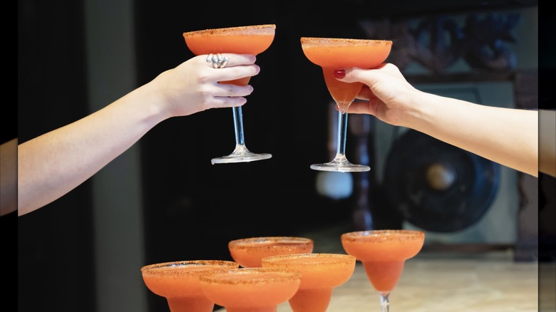 Two people toasting with colorful margaritas