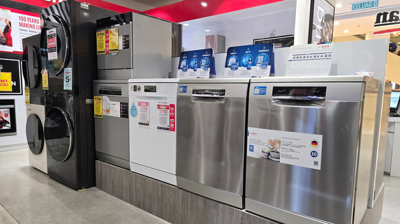 Several dishwashers lined up next to each other in an electronics store.