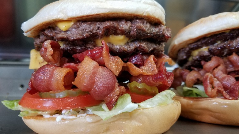 Burgers stuffed with multiple patties, cheese, bacon, tomatoes, and other toppings at Champ Burger in Houston