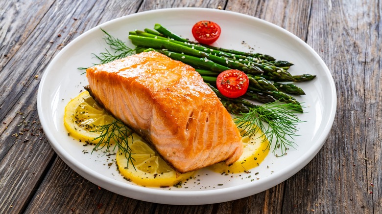 A piece of salmon on a plate with lemon and asparagus