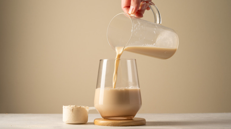 Protein powder in scoop next to a latte being poured