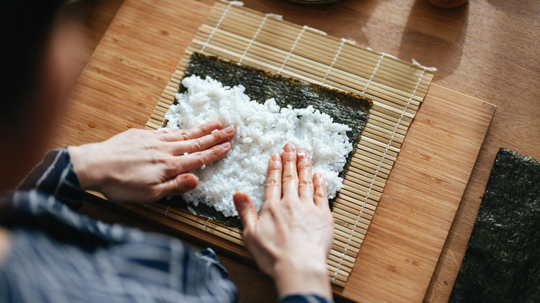 person making sushi, rice spread on seaweed