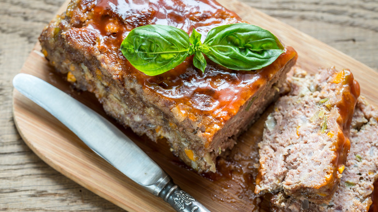 Meatloaf with barbecue sauce and basil leaves.