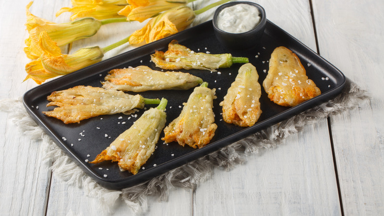 Fried zucchini blossoms on a black plate.