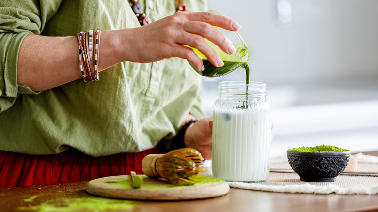 Woman pouring whisked matcha into a glass of milk
