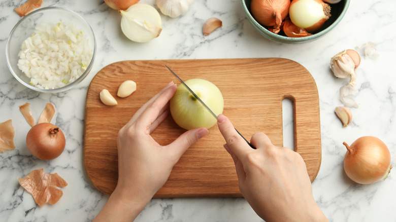 person chopping onions on a cutting board
