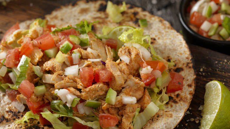 A chicken taco is stuffed with veggies and chicken