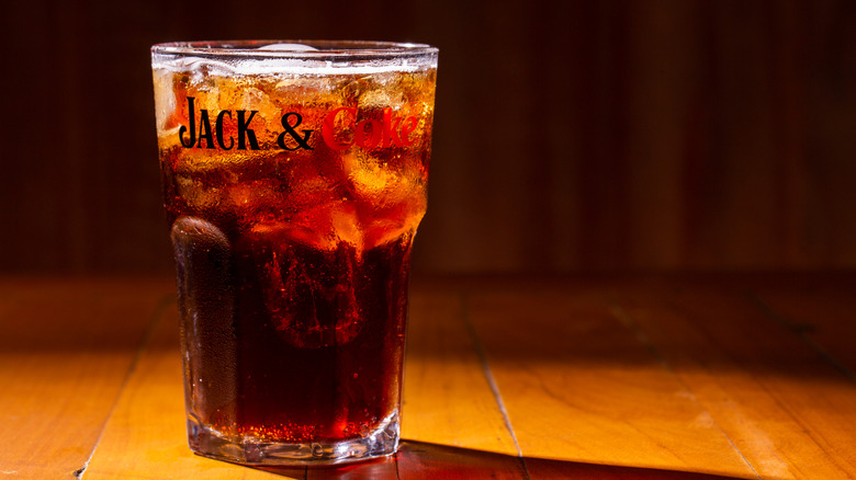 A Jack and Coke in a branded glass is seen on a bar.