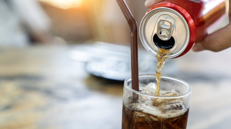 a can of coke being poured into a glass